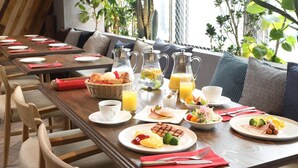 Um buffet de café da manhã com diversos pratos, bebidas e uma área de estar aconchegante com plantas.