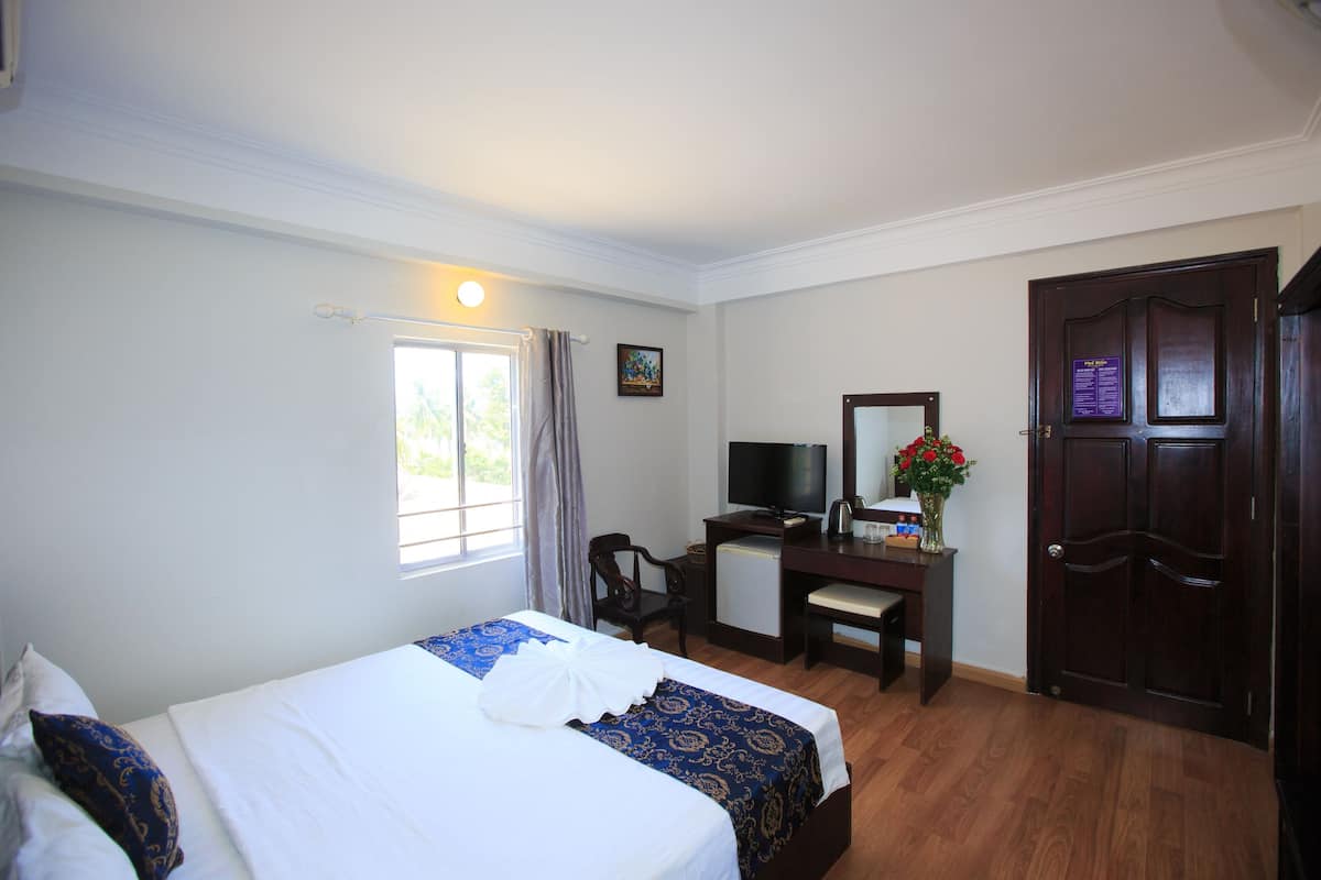 Une chambre d’hôtel avec un lit, un bureau, une télévision et une porte.