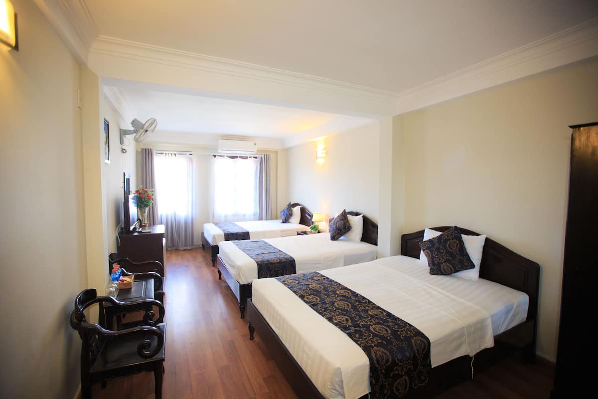 Une chambre d’hôtel avec deux lits, un bureau et une chaise.