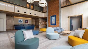 A modern lobby with a reception desk, seating areas, and a large artwork on the wall.