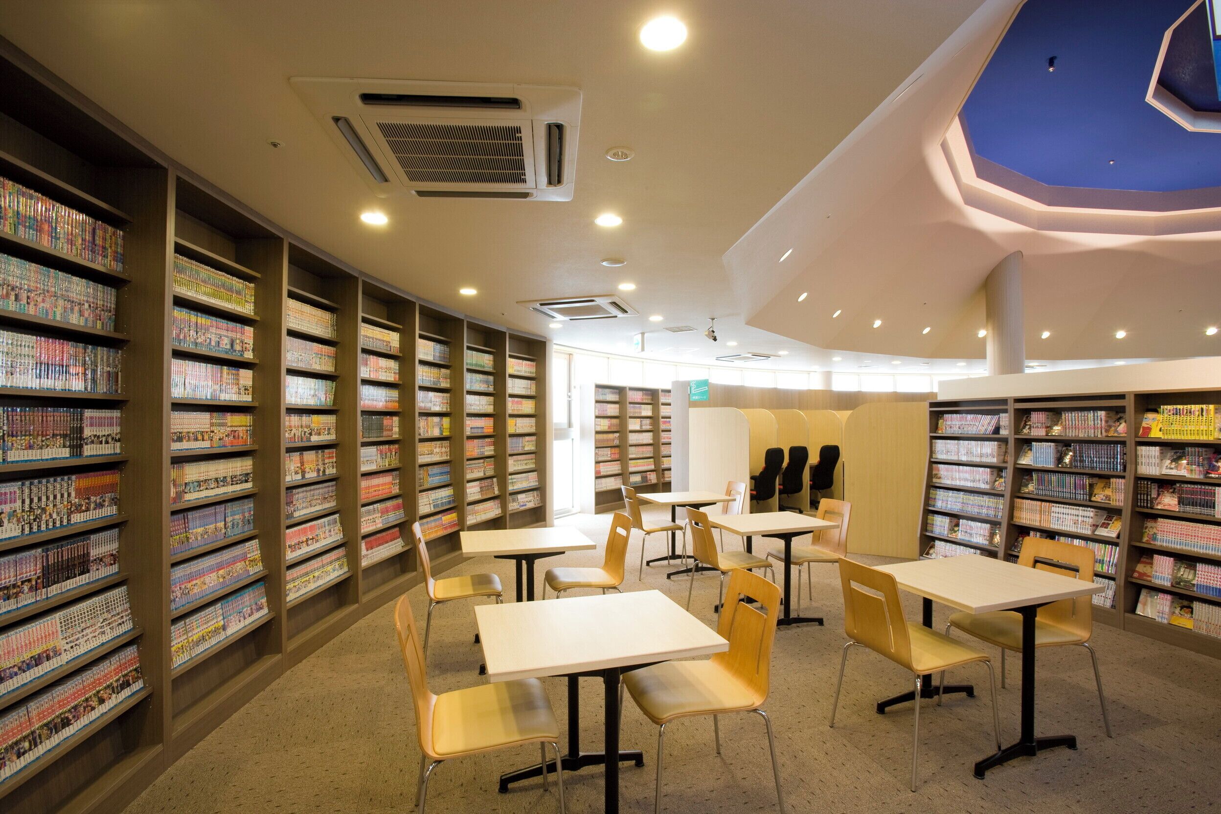 Eine Bibliothek mit Bücherregalen, Tischen und Stühlen.