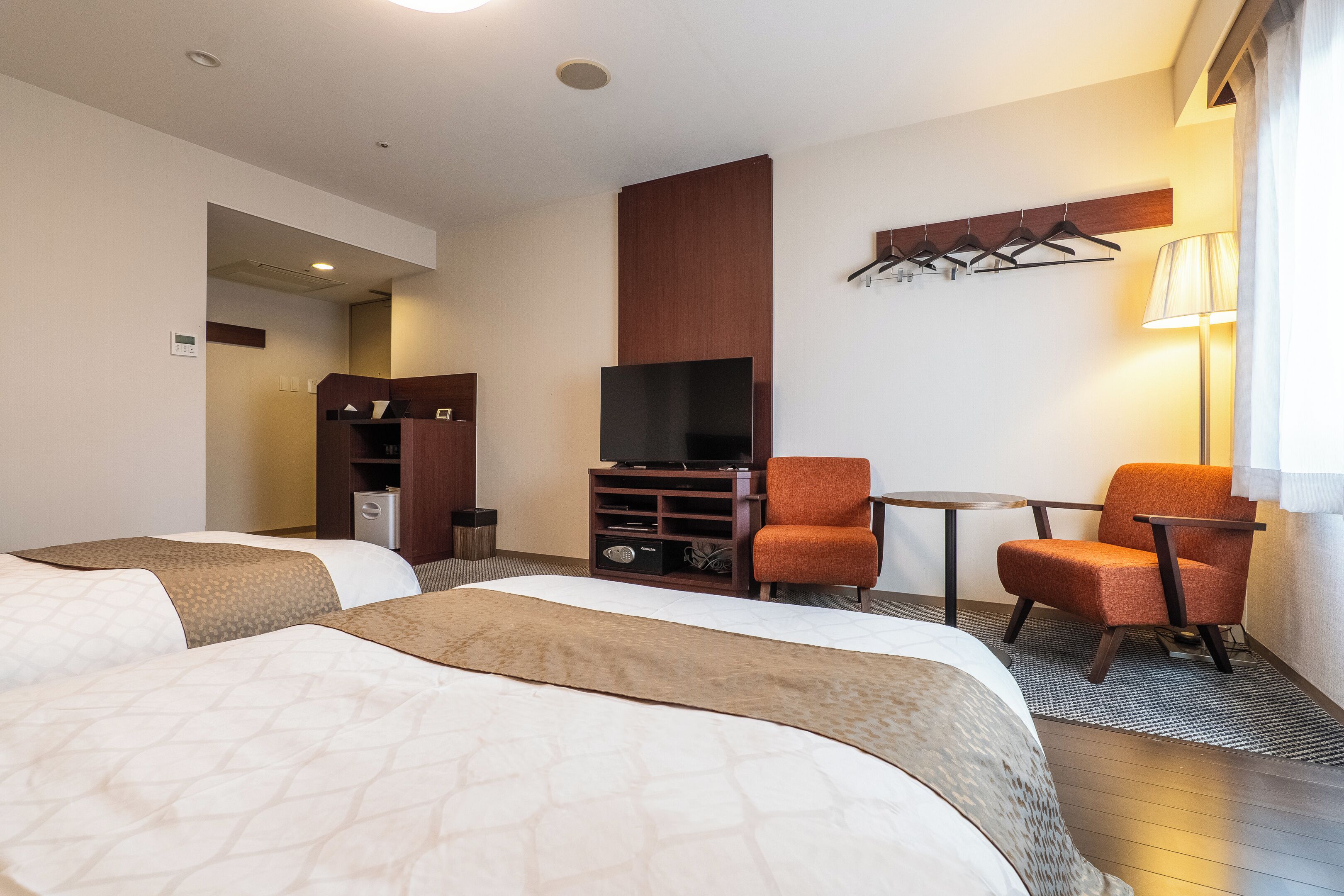 Habitación de hotel con dos camas, un televisor, una mesita y dos sillas.