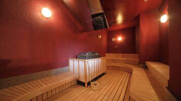 A sauna with wooden benches and a central table with a basket.