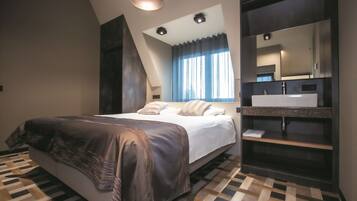 A modern bedroom with a bed, a large mirror, and a bathroom vanity.