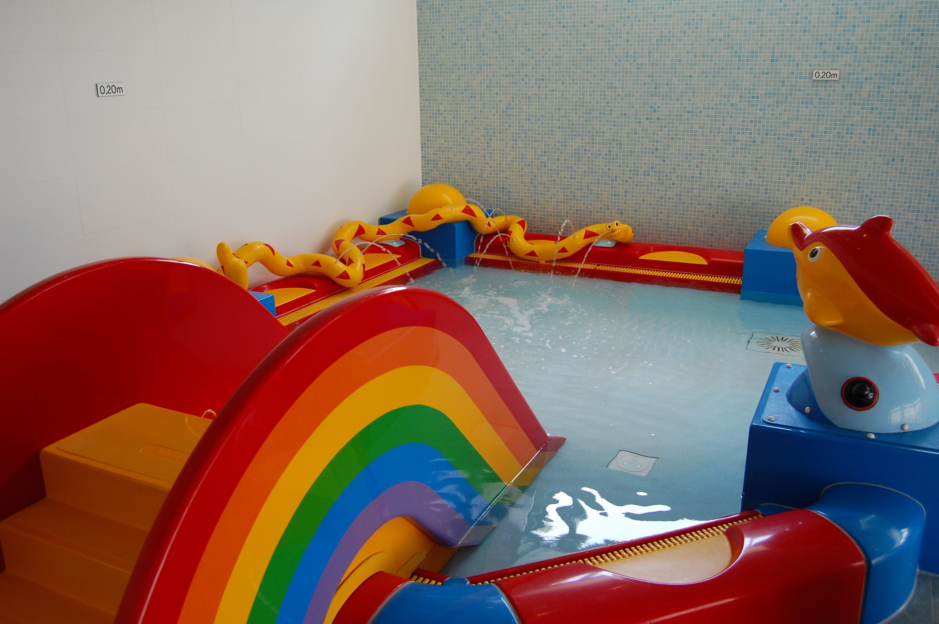 Een speelruimte voor kinderen met een glijbaan, een zwembad en diverse speelgoed.