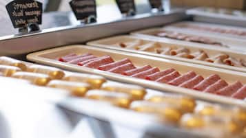 Exposição de alimentos com diversos tipos de carne fatiada e uma placa indicando 'Spitzwurst, salsicha fatiada'.