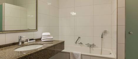 Un baño moderno con encimera de granito, dos lavamanos, un espejo grande, una bañera y una ducha.