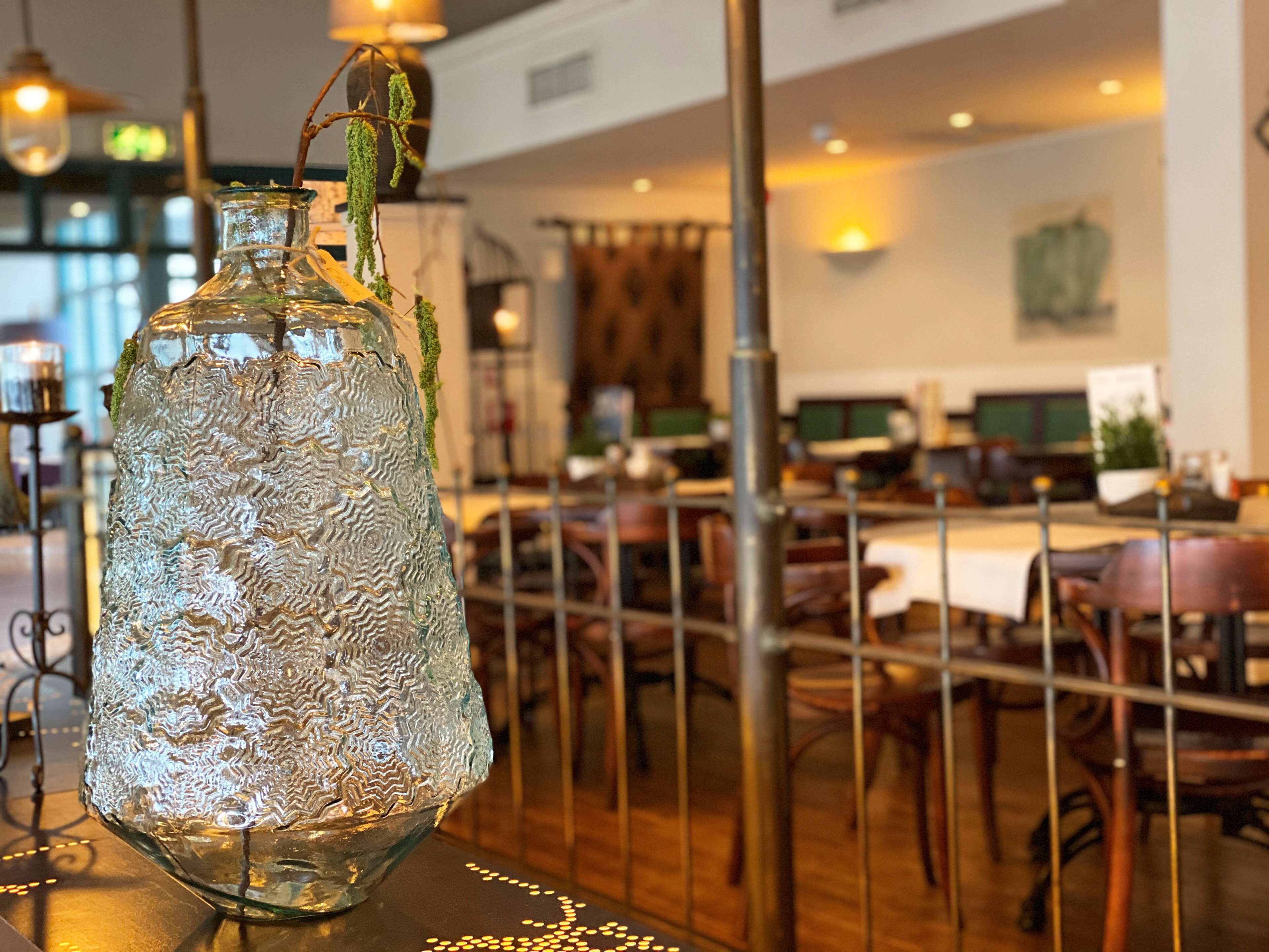 A glass bottle with a textured design on a table in a restaurant setting.