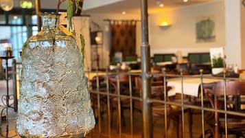 A glass bottle with a textured design on a table in a restaurant setting.