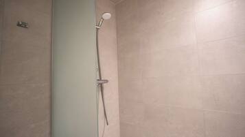 A shower with a handheld showerhead and a wall-mounted control.