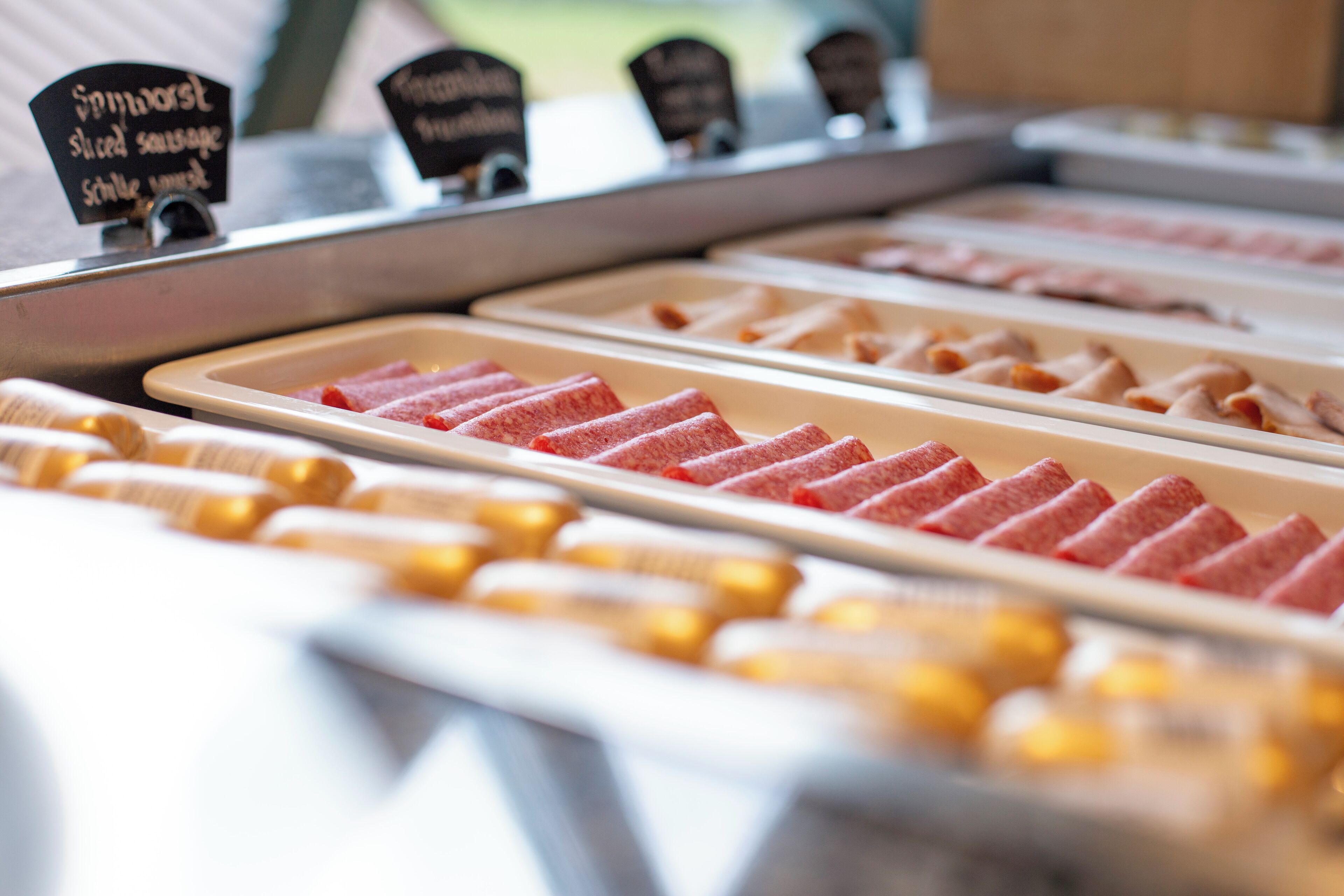 A deli counter with various sliced meats displayed in trays.
