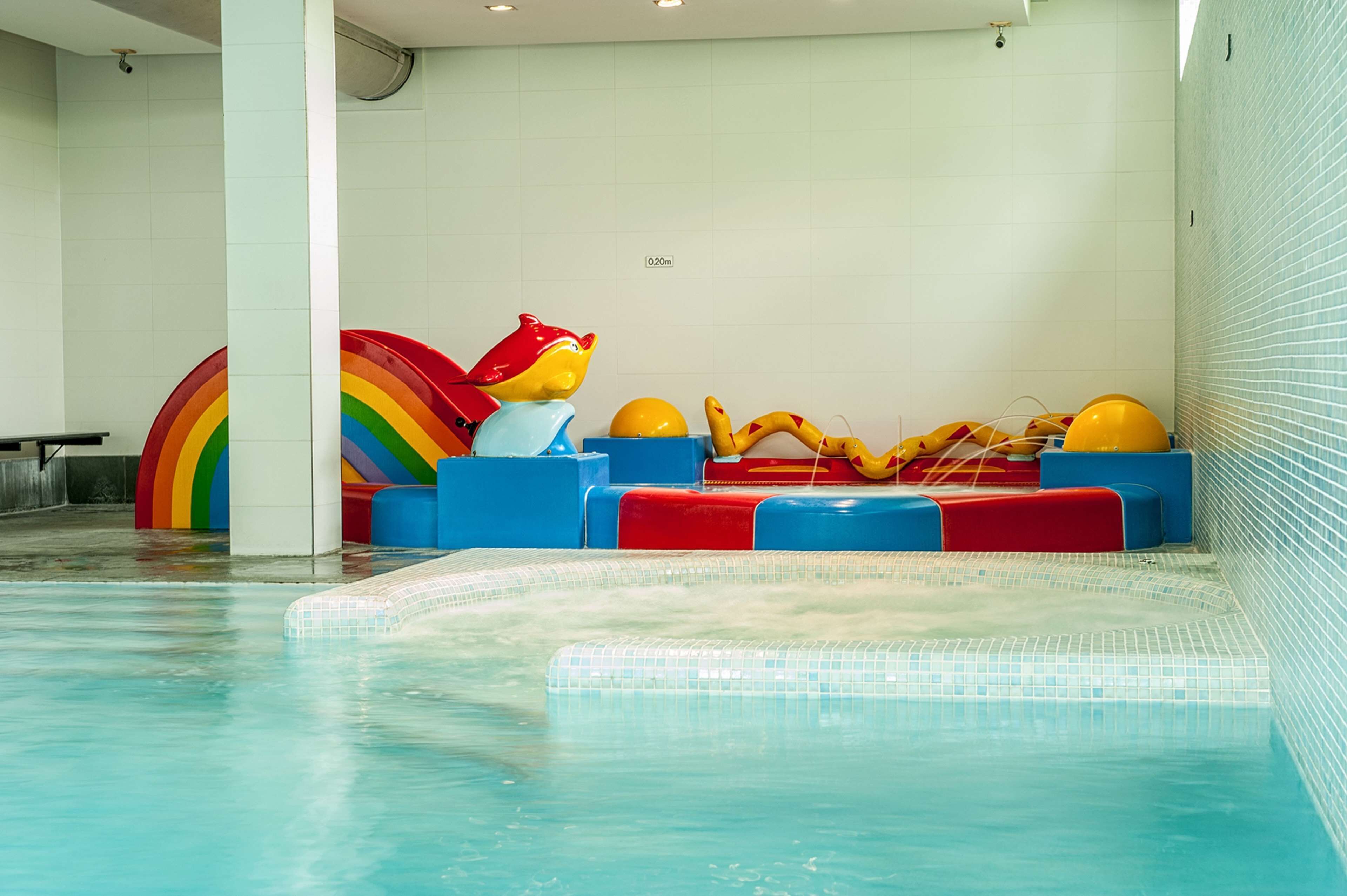 A swimming pool area with colorful seating and a rainbow decoration.