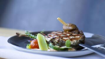 Un plato con carne a la parrilla, verduras y una guarnición.