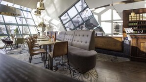 A modern interior with a large window, a sofa, a dining area, and a wooden bookshelf. - Best Western Hotel Nobis Asten (Asten)