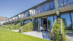 A modern hotel with multiple balconies, outdoor seating, and a well-maintained lawn. - Best Western Hotel Nobis Asten (Asten)