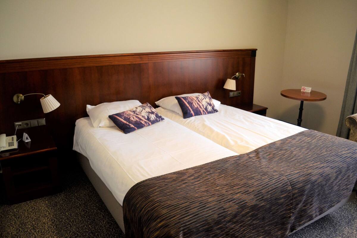 Une chambre d’hôtel avec un lit double, deux oreillers, une table de chevet avec une lampe, une petite table ronde et un téléphone.
