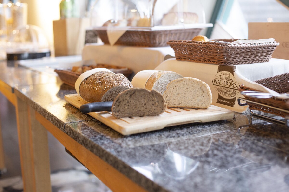 A variety of breads and pastries on a counter, with a knife and a cutting board.