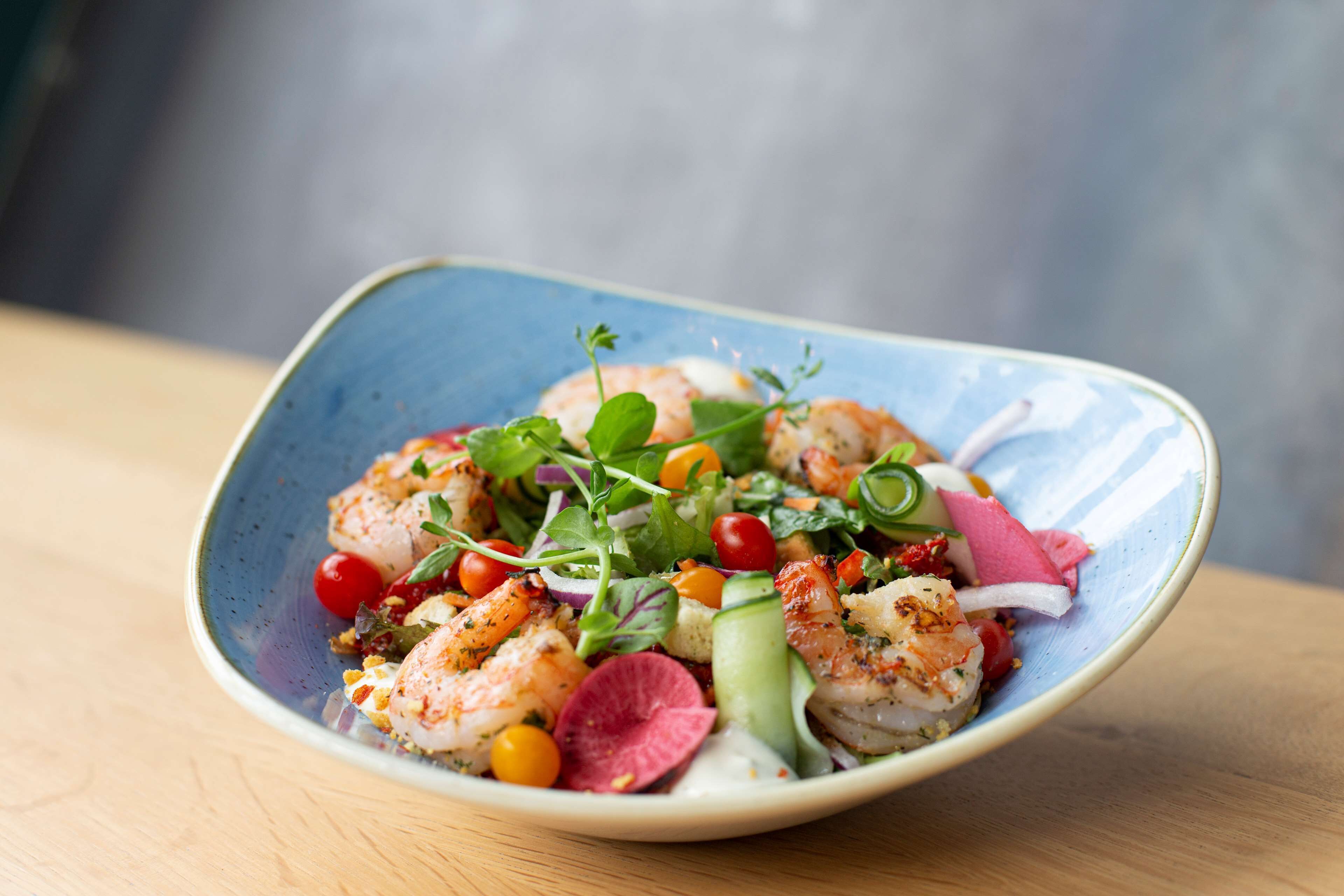 A seafood dish with shrimp, vegetables, and a creamy sauce on a ceramic plate.