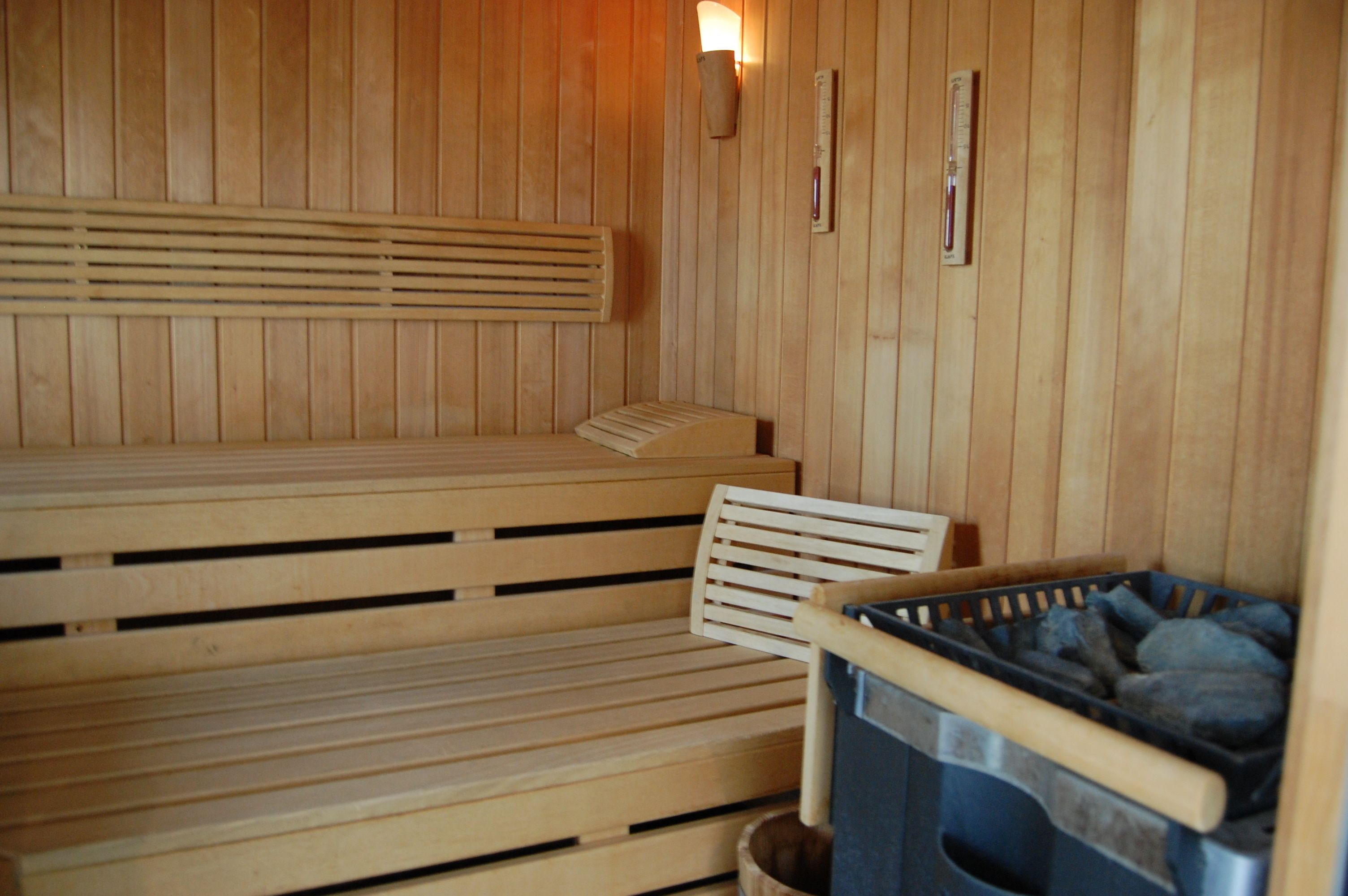 A wooden sauna with benches and a wall-mounted heater.