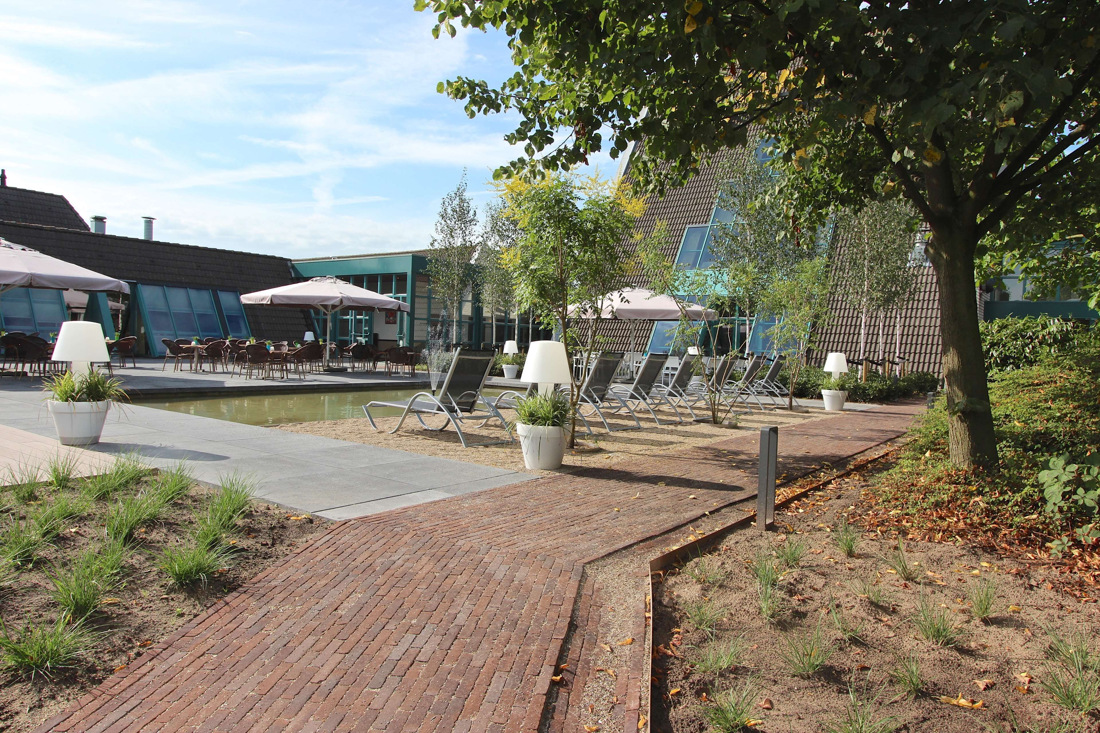 A courtyard with outdoor seating, potted plants, and a brick pathway.
