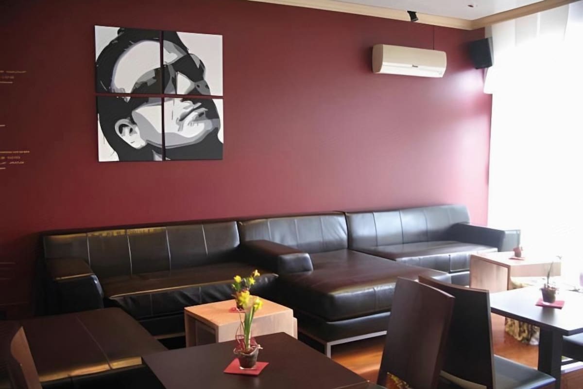 Een modern interieur met een leren bank, houten tafels en een wandgemonteerde airconditioner.