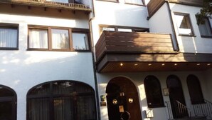 A two-story building with a white facade, large arched windows, and a wooden balcony. - Hotel Kelkheimer Hof (Kelkheim)