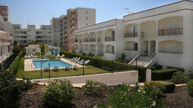 A residential building with a swimming pool, multiple balconies, and a well-maintained garden. - Apartamentos Kings (Loule)