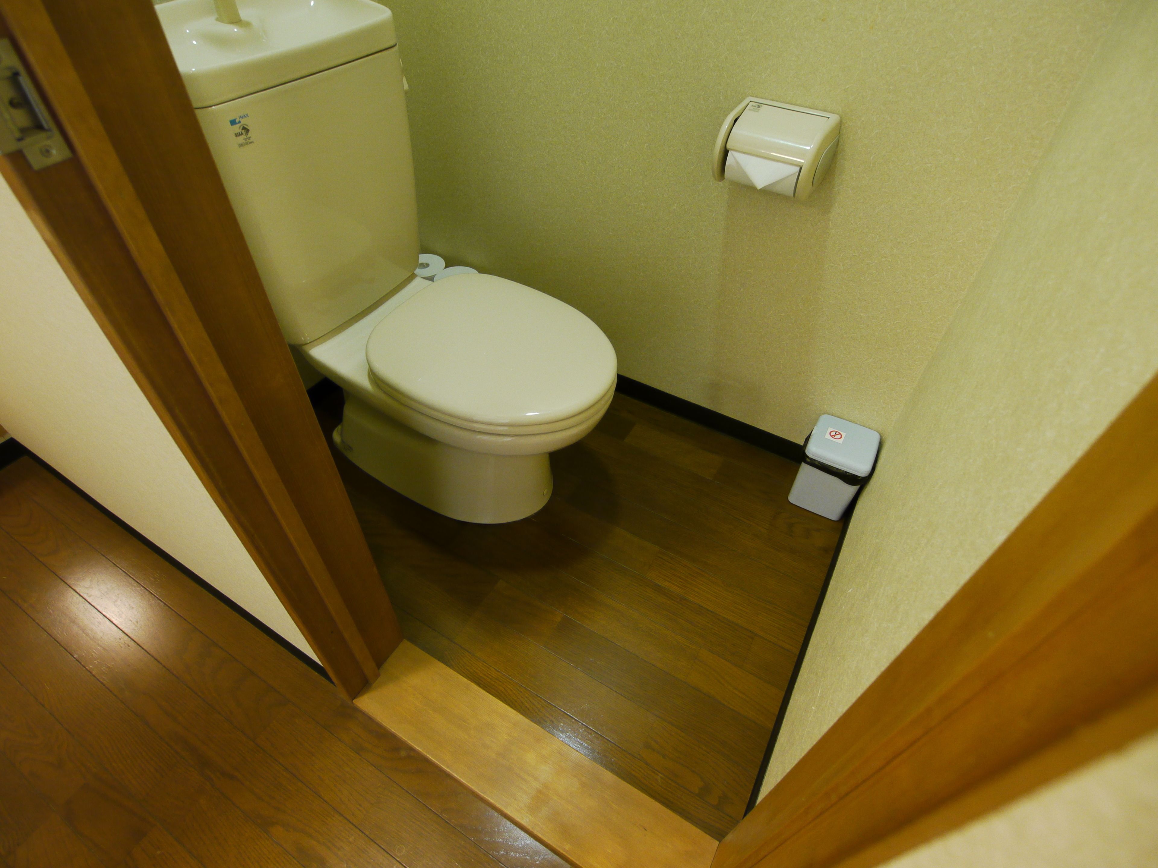 Ein kleines, schmales Badezimmer mit Toilette, Mülleimer und Papierhandtuchspender.