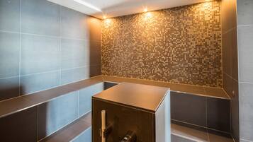 A modern bathroom with a tiled wall, a built-in shower, and a bench.