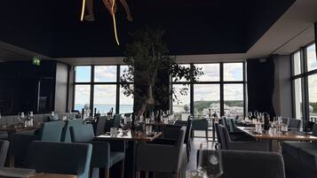 Ein Restaurant mit Meerblick, großen Fenstern und moderner Einrichtung.