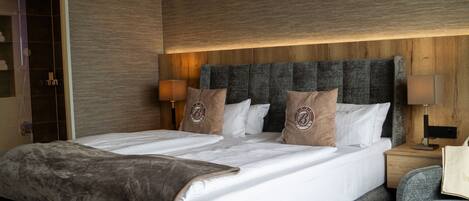 Ein Hotelzimmer mit einem großen Bett, zwei Nachttischen, einem kleinen runden Tisch und einer Sitzecke mit einem Sessel.