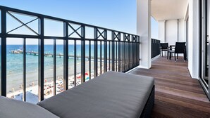 A balcony with a view of the beach and pier, a wooden floor, and a seating area with a table and chairs. - Bayside (Scharbeutz)