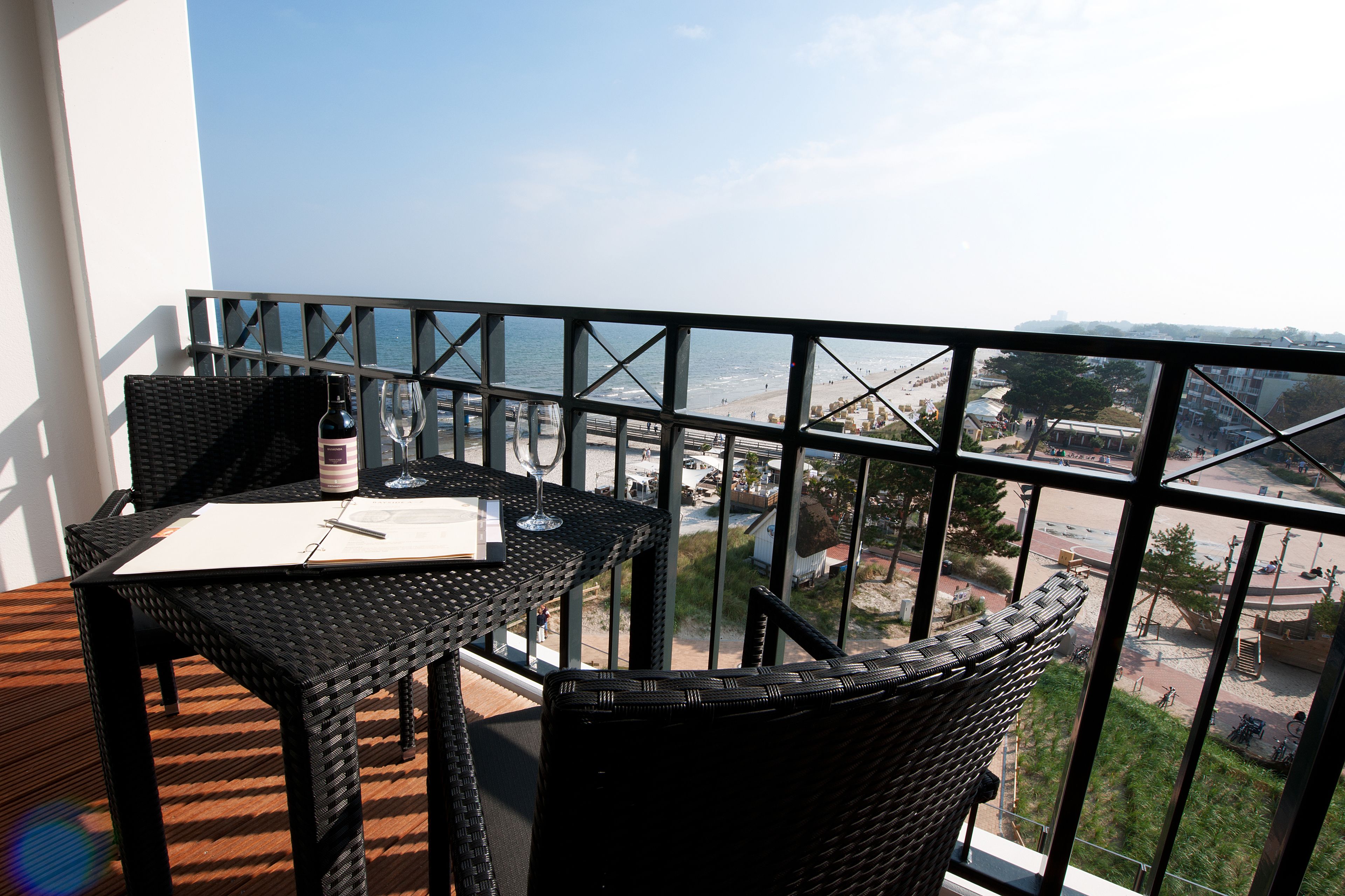 Un balcón con mesa y sillas, con vistas a la playa y al paisaje urbano.