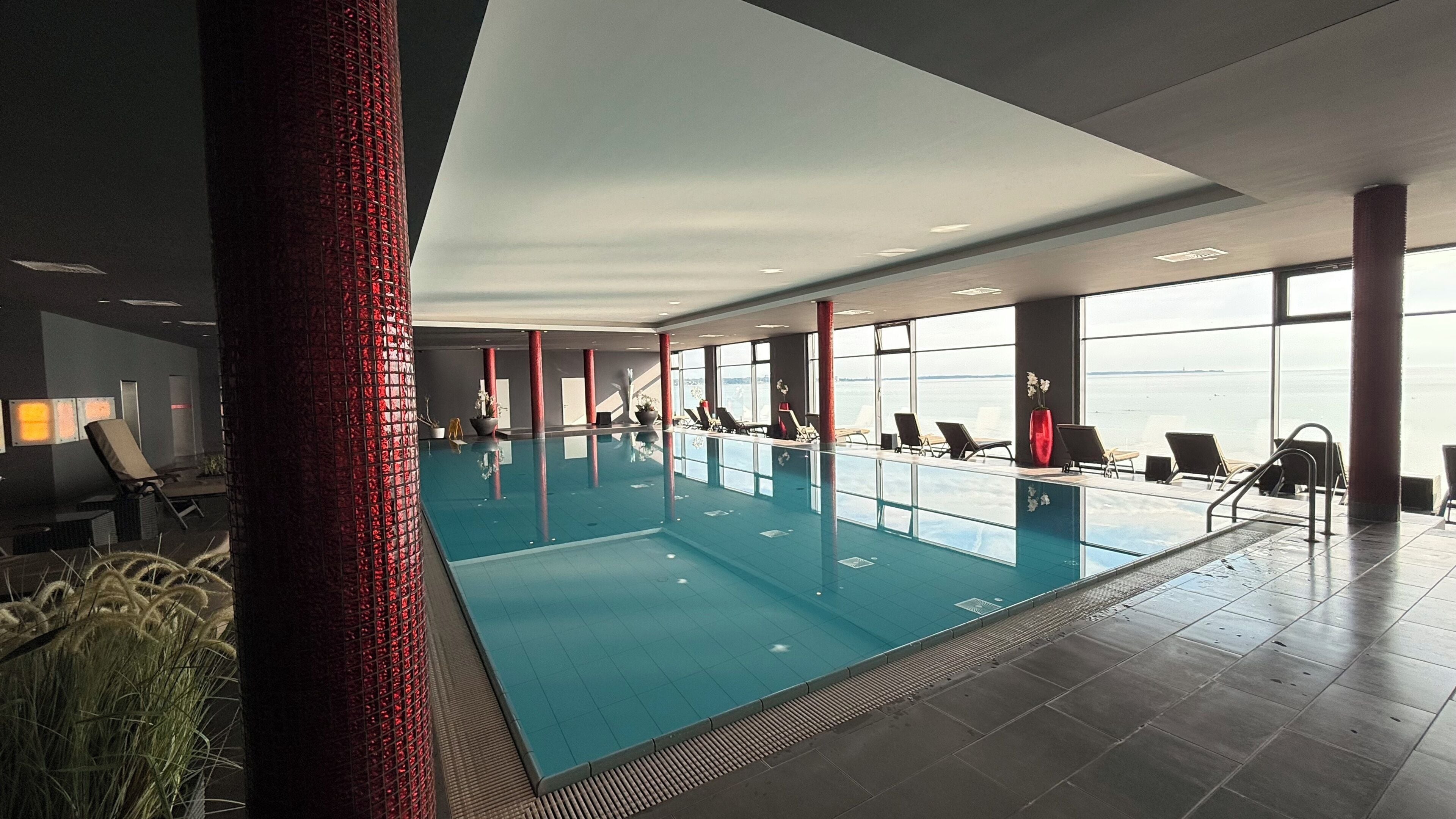 A swimming pool with lounge chairs and a view of the sea.