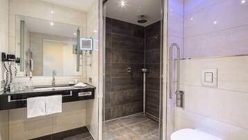 A modern bathroom with a glass-enclosed shower, a vanity with a mirror, and a toilet.