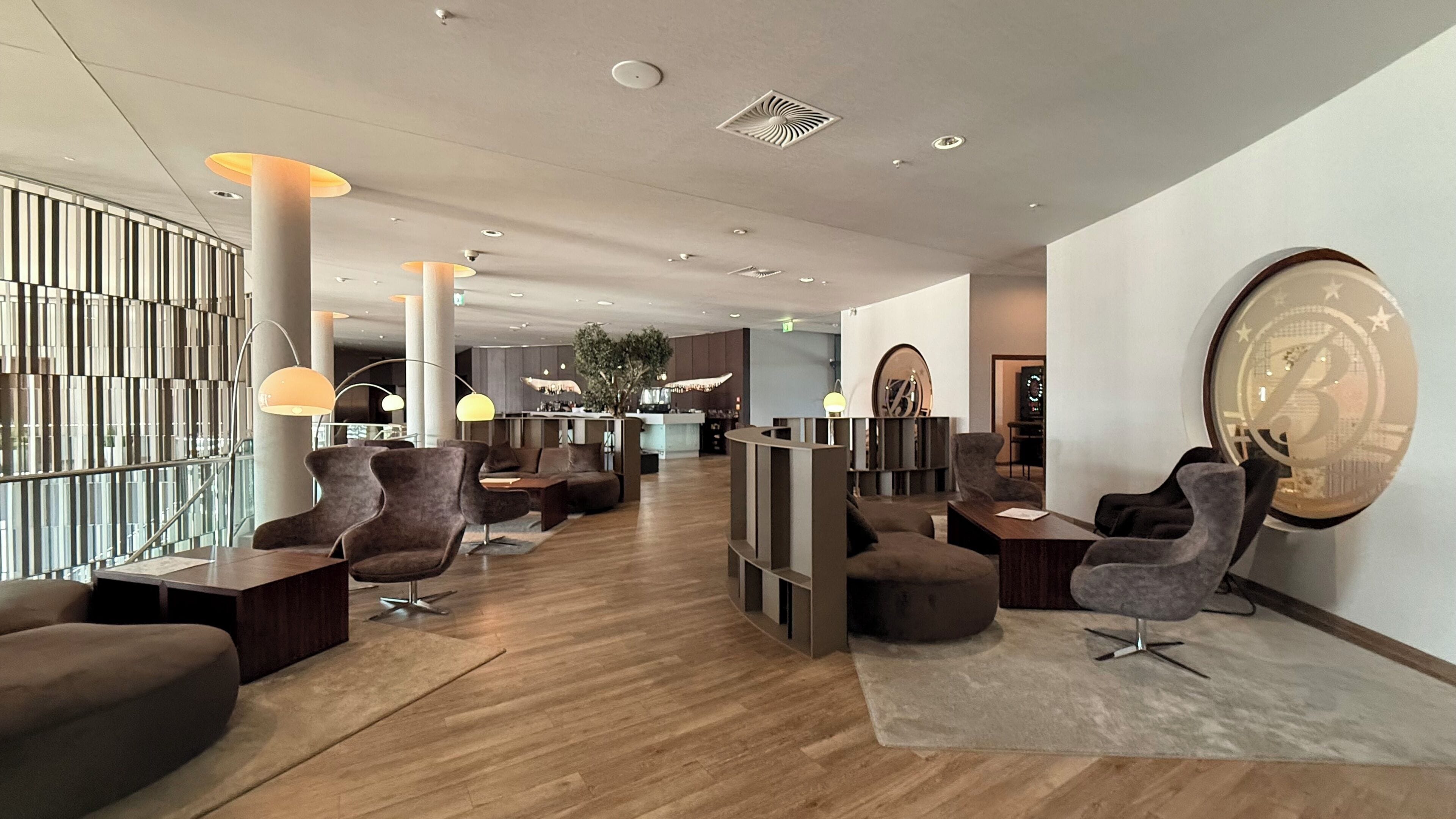 Eine moderne Lobby mit Sitzbereichen, einem Empfangsschalter und einem großen Wandkunstwerk.