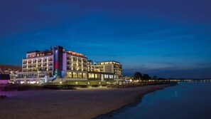 Hotel com vários andares e varandas, situado à beira-mar.
