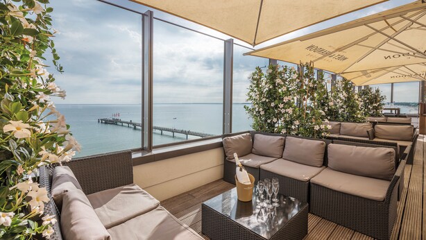 A balcony with wicker furniture, a glass table, and a bottle of champagne. - Bayside (Scharbeutz)