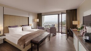 Quarto de hotel com uma cama grande, uma escrivaninha e vista para a praia.