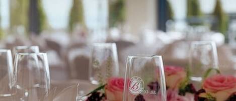 A table set for a formal event with clear glassware, silverware, and pink floral centerpieces.