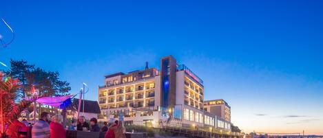 A hotel with multiple floors, outdoor seating, and a beach view.