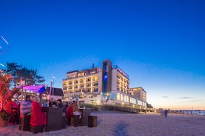 A hotel with multiple floors, outdoor seating, and a beach view.