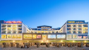 A multi-story hotel with a central atrium, large windows, and a sandy ground floor. - Bayside (Scharbeutz)