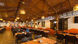 A restaurant with multiple tables and chairs, wooden ceiling, and decorative wall panels. - Martin's Comfort (Betalbatim)
