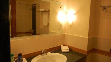Un baño de hotel con un espejo grande, un lavamanos y un perchero para toallas.