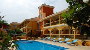 A pool area with lounge chairs and a building with balconies. - Martin's Comfort (Betalbatim)