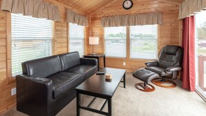 A cozy room with a leather sofa, a small table, a leather chair, and a clock on the wall. - Sun Retreats Gun Lake (Hopkins)