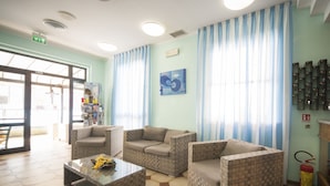 A reception area with a seating arrangement, a fire extinguisher, and a wall-mounted key rack. - Hotel Luciana (Rimini)