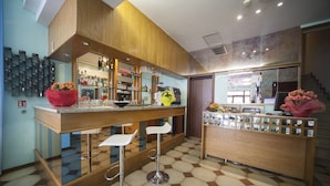 A modern bar area with a wooden counter, bar stools, and a tiled floor. - Hotel Luciana (Rimini)