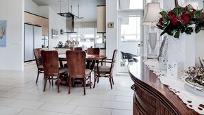 A modern kitchen with a dining area, featuring a large island with a vase of red roses. - Guesthouse Bjarney (Selfoss)